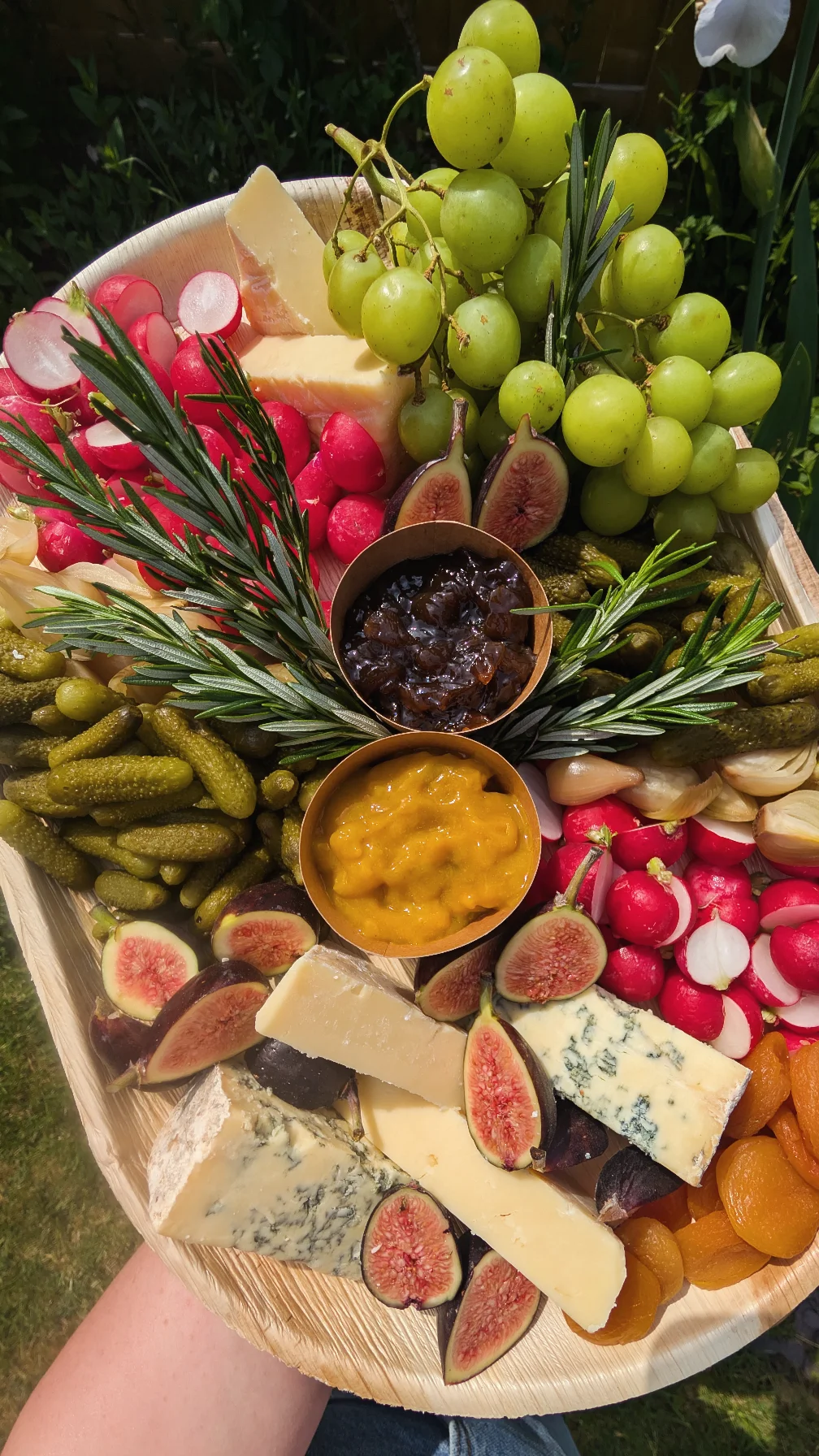 Cheese platter with grapes, figs, cornichons and chutneys